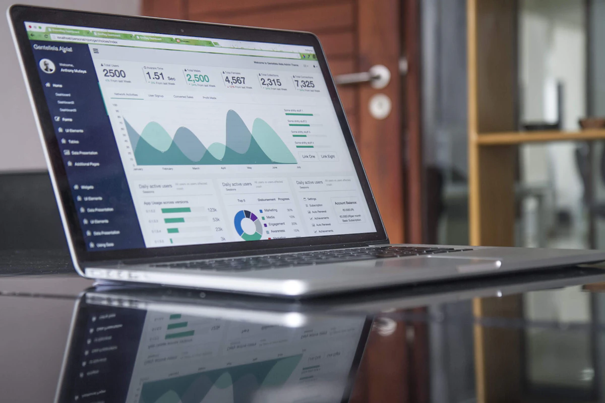 Laptop di meja kaca dengan grafik analitik pada layarnya